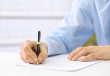 Hands writing on a legal document