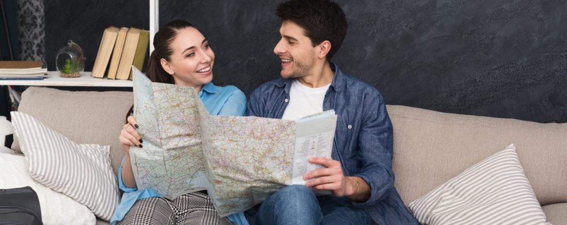 A man and a woman look at a map together as they prepare for a trip.